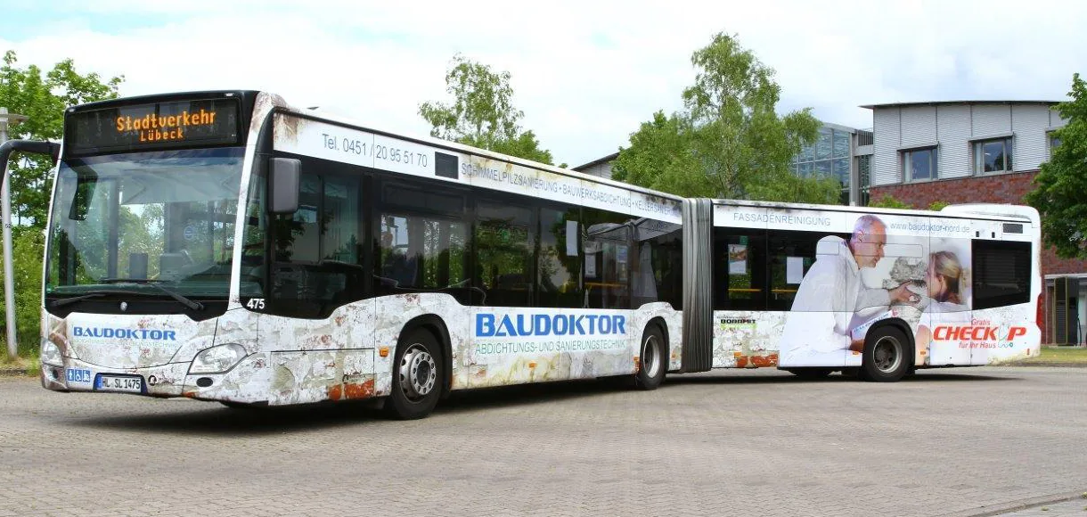 Gelenkbus des Stadtverkehrs Lübeck in einer Vollwerbung mit dem Schriftzug BAUDOKTOR und dem Zusatz „Abdichtungs- und Sanierungstechnik“.